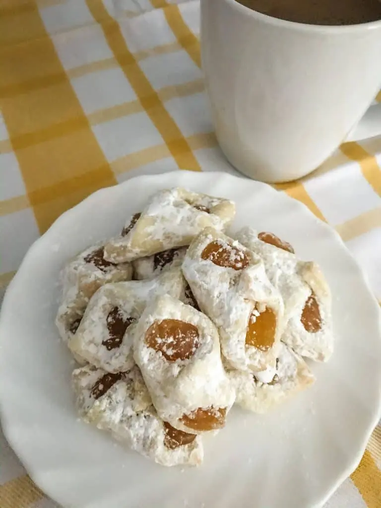apricot kolaczki cookies on white plate with mug of coffee on yellow and white towel