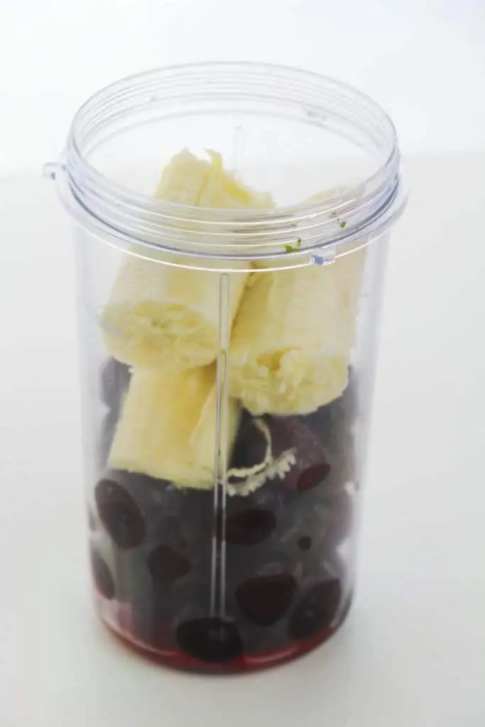 frozen cherries and bananas in plastic blender cup