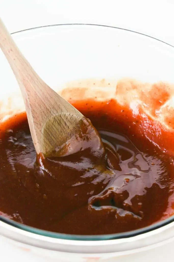 homemade bbq sauce in clear glass bowl with wooden spoon