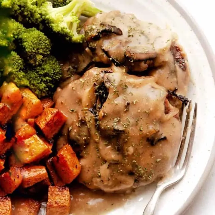 Chicken Salisbury Steak with gravy on white plate with broccoli and sweet potatoes