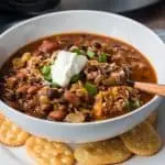 white bowl containing irish chili on white plate with crackers