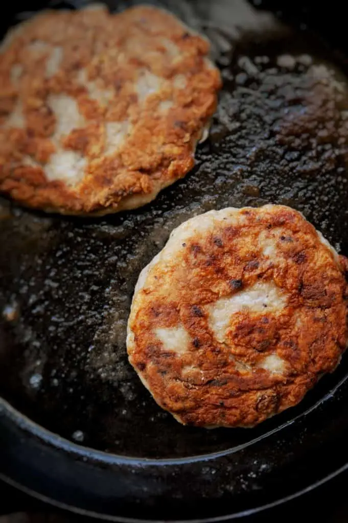 chicken salisbury steak patties cooking in cast iron skillet