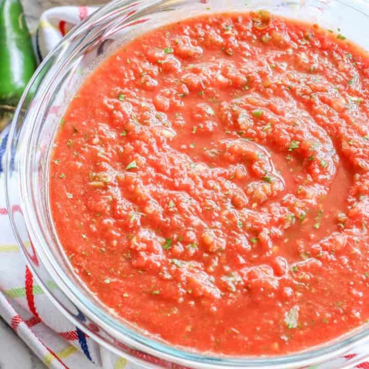 close-up of bowl of homemade salsa with whole jalapeno in background