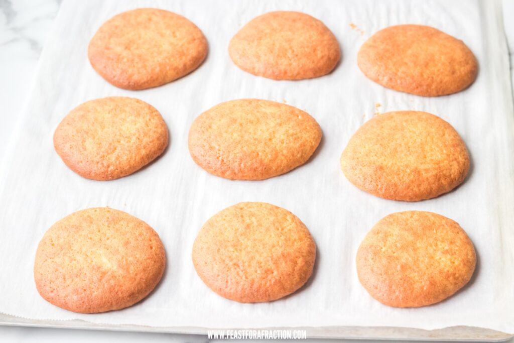Freshly baked whoopie pies cooling on a parchment-lined baking sheet.