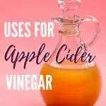 glass bottle of apple cider vinegar on pink background