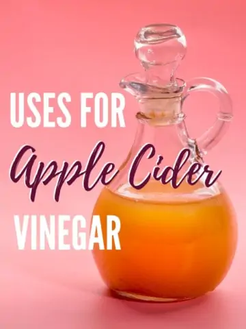 glass bottle of apple cider vinegar on pink background