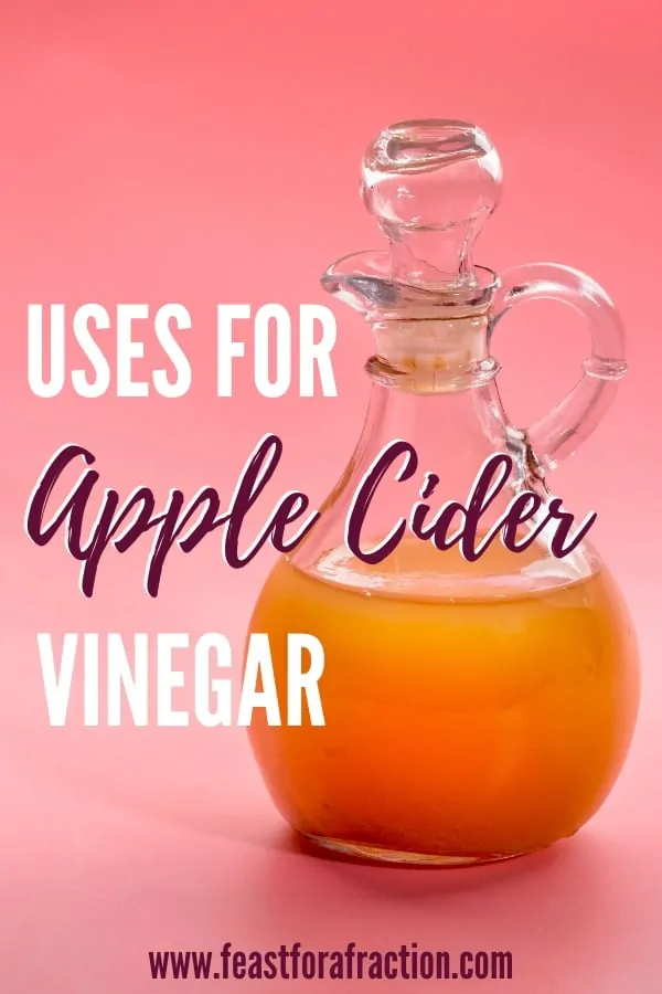 glass bottle of apple cider vinegar on pink background