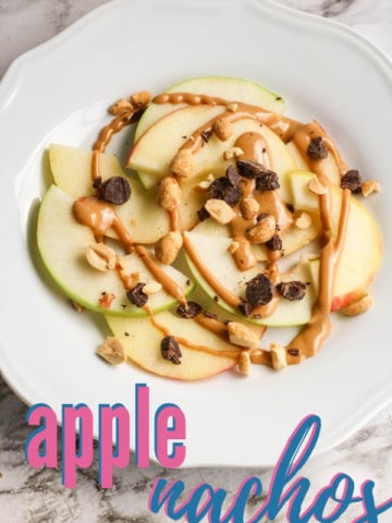 sliced apples with peanut butter and chocolate on white plate with title text "apple nachos"