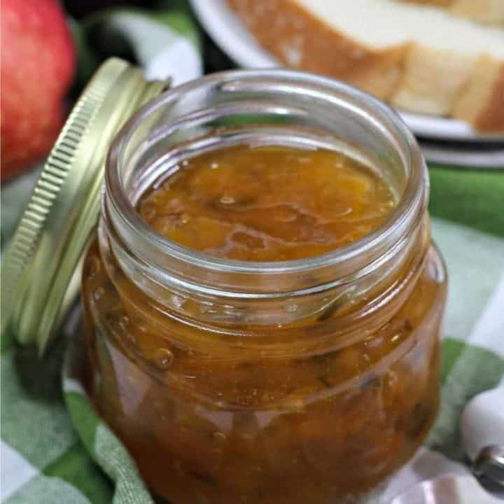 jar of peach jalapeno jam on green and white cloth napkin