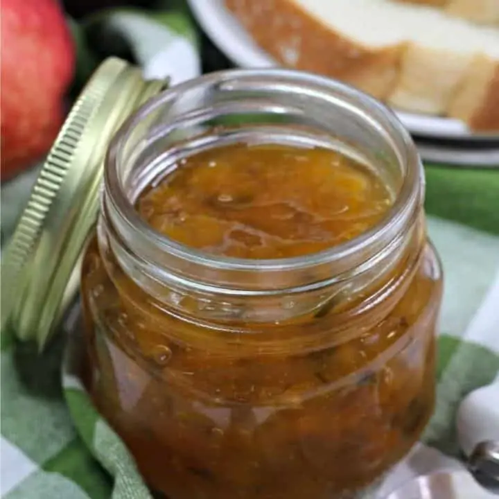 jar of peach jalapeno jam on green and white cloth napkin