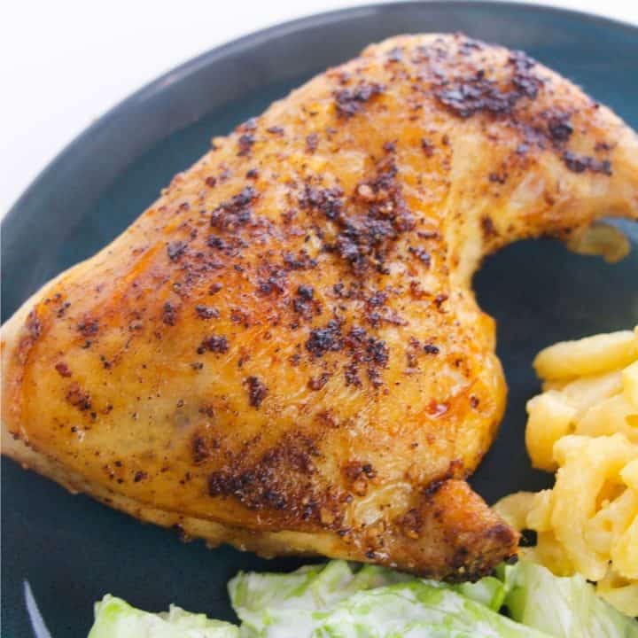 sqaure image of baked chicken leg quarter with macaroni and cheese and salad