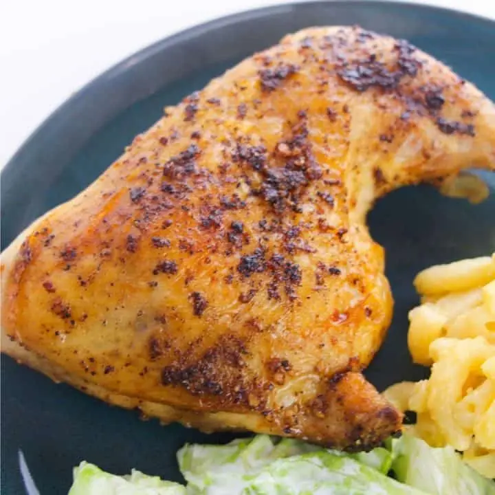 sqaure image of baked chicken leg quarter with macaroni and cheese and salad