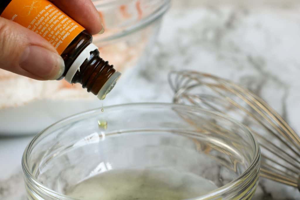 bottle of orange essential oils being poured into a glass bowl