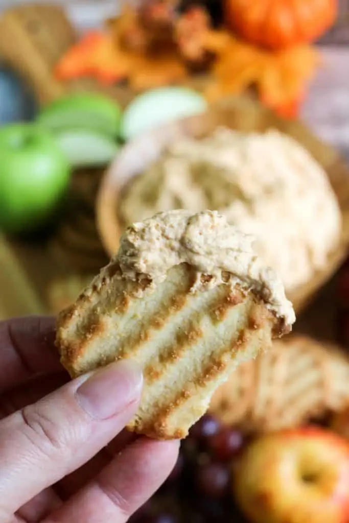 hand holding shortbread cookie dipped in pumpkin fluff dip