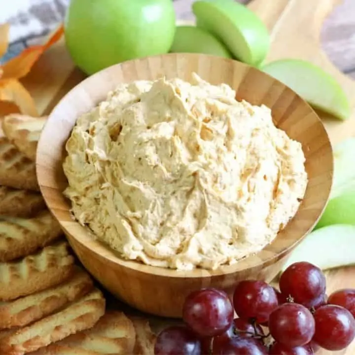 close-up of pumpkin fluff dip in wooden bowl with grapes and cookies