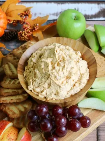 pumpkin fluff dip in wooden bowl with grapes, apple slices and shortbread cookies
