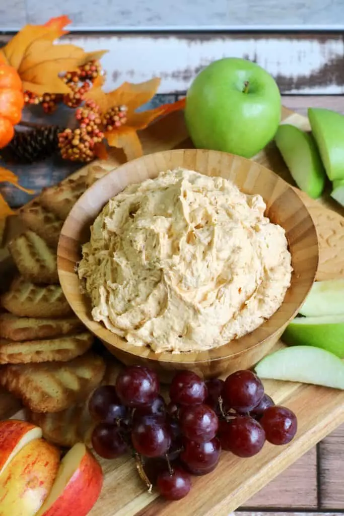 pumpkin fluff dip in wooden bowl with grapes, apple slices and shortbread cookies