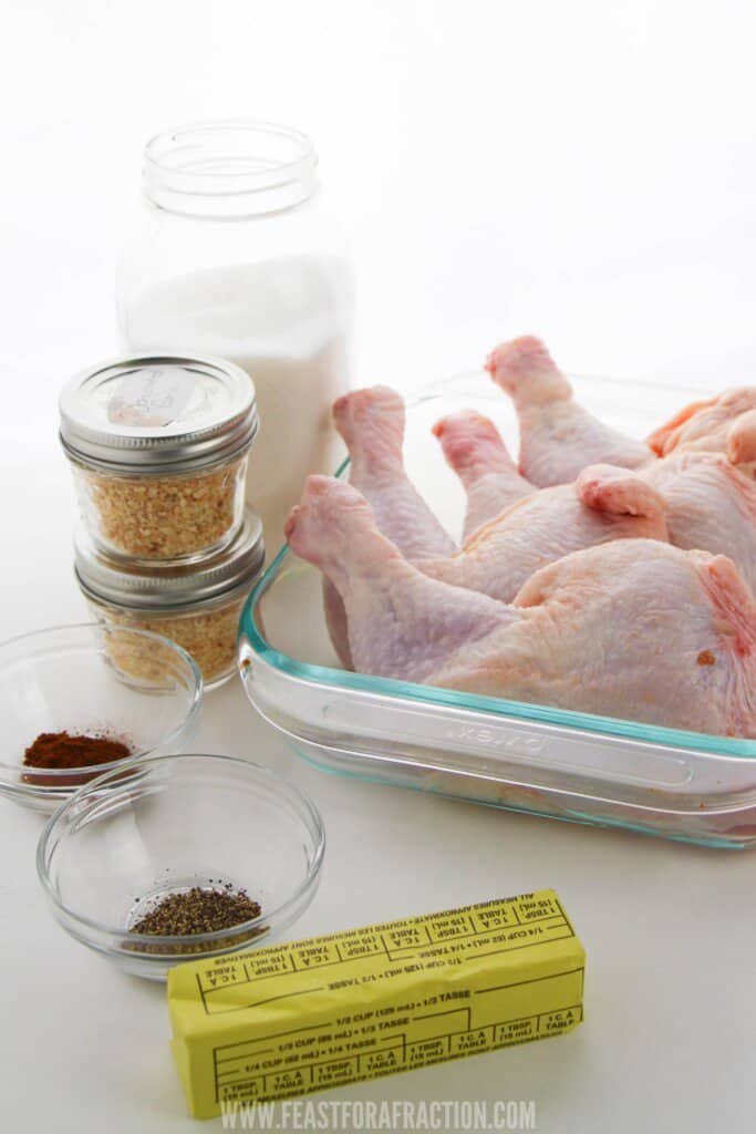 chicken leg quarters in glass baking dish with spices and stick of butter.