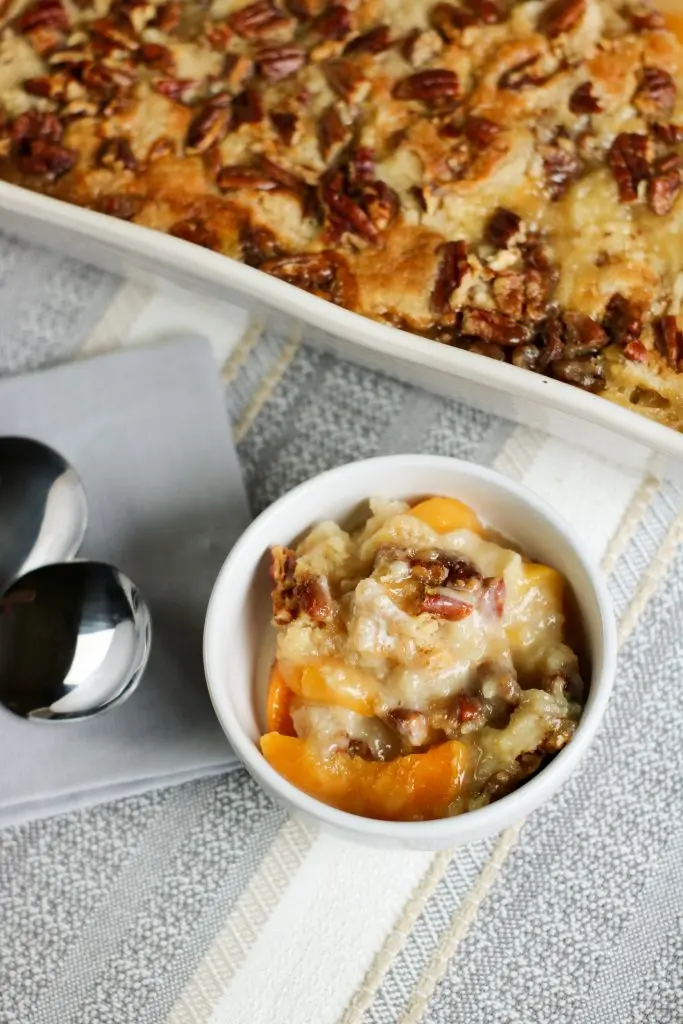 overhead of white chocolate peach dump cake in white bowl with two spoons