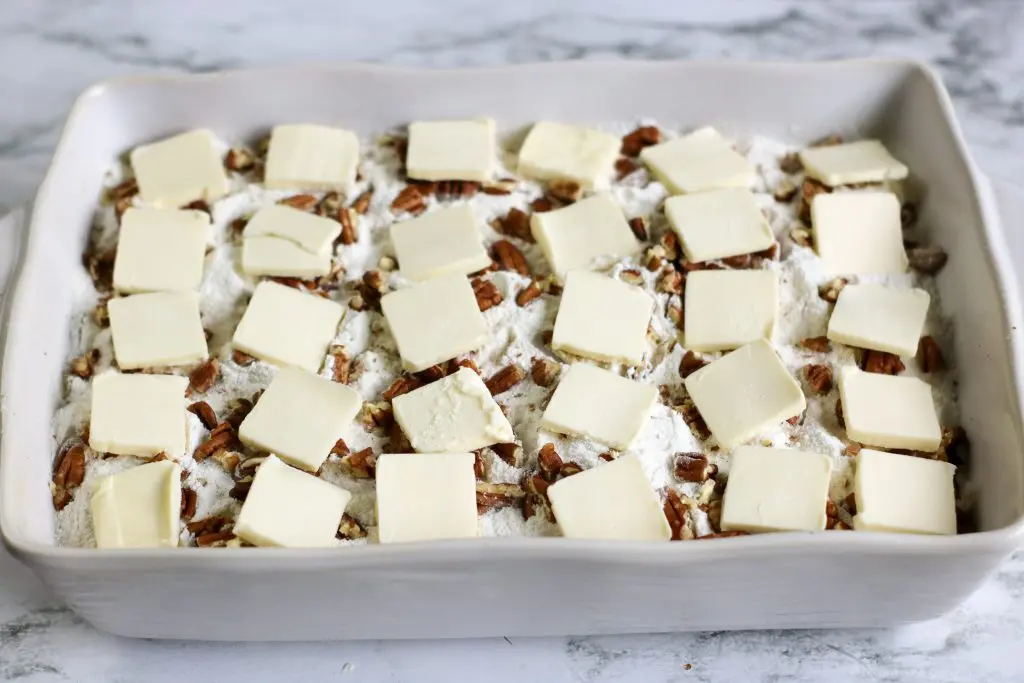 white baking dish with white chocolate peach dump cake ingredients layered