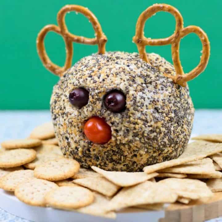 everything bagel cheese ball decorated like a reindeer on bamboo platter with crackers