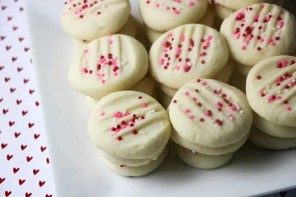 whipped shortbread cookies topped with pink nonpareils on square white plate