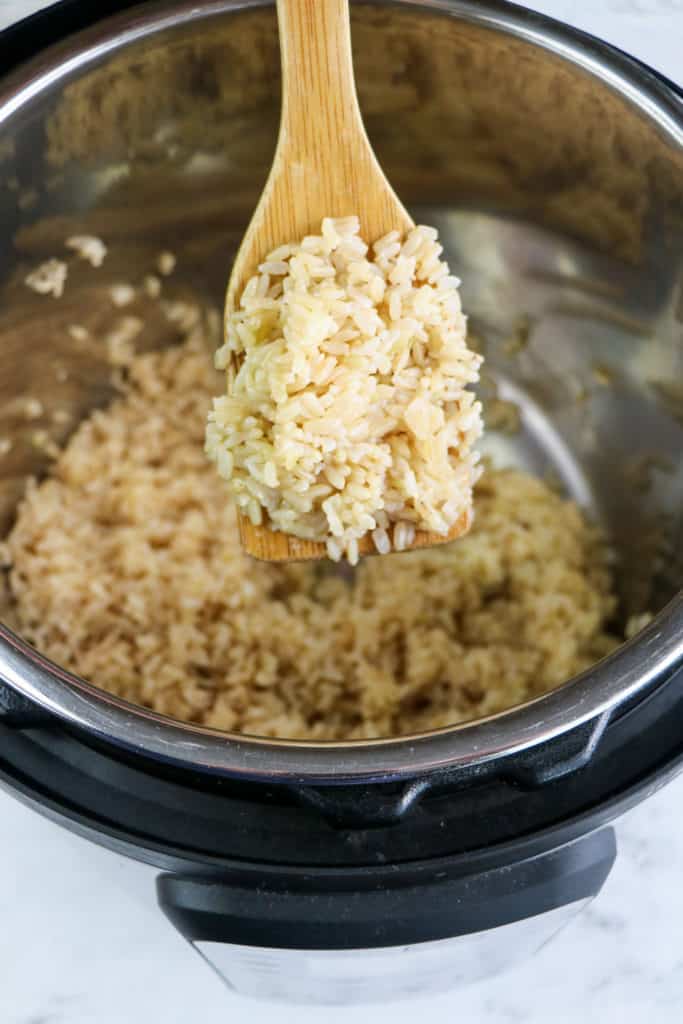 wooden spoon of cooked brown rice in instant pot