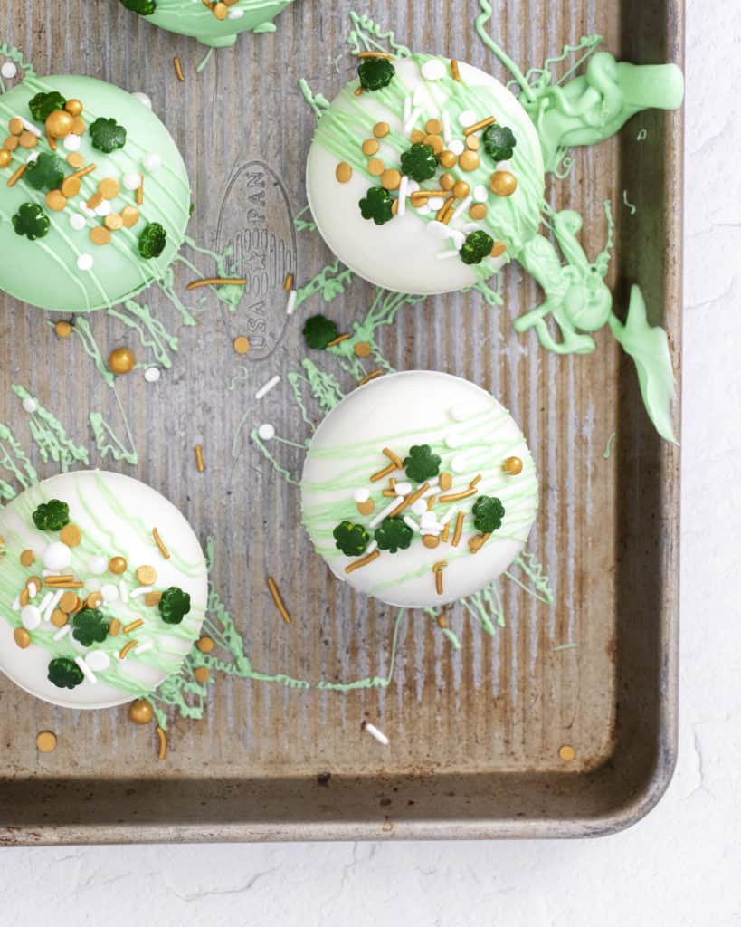 peppermint hot cocoa bombs on sheet pan topped with shamrock sprinkles