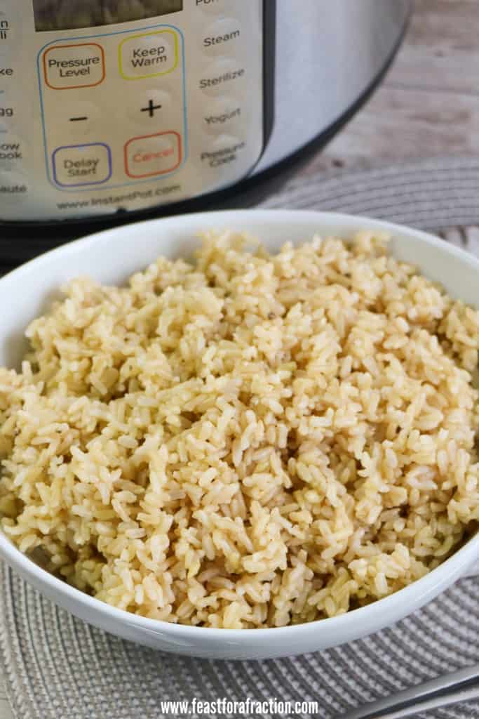 brown rice in round white bowl with instant pot in background on gray placemat