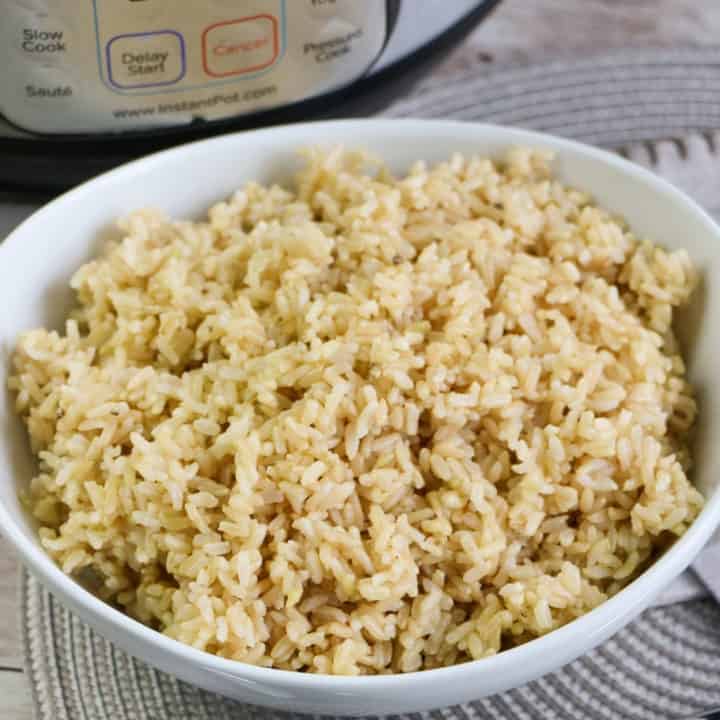 square image of cooked brown rice in white bowl with instant pot in background