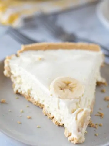 slice of banana pudding pie on grey plate with yellow napkin