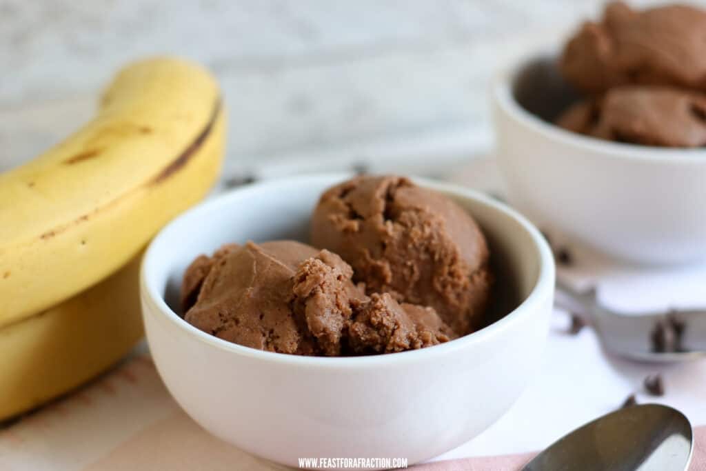 dairy free chocolate peanut butter banana ice cream in white bowls with spoon and whole bananas