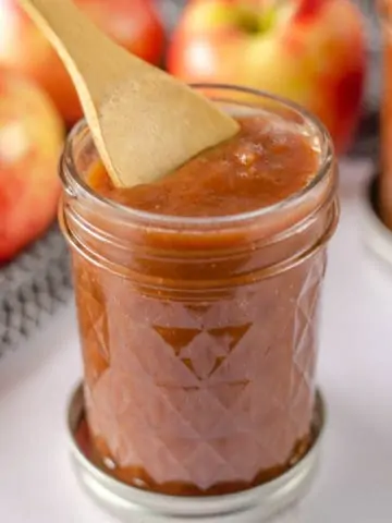 instant pot apple butter in glass jar with wooden spoon