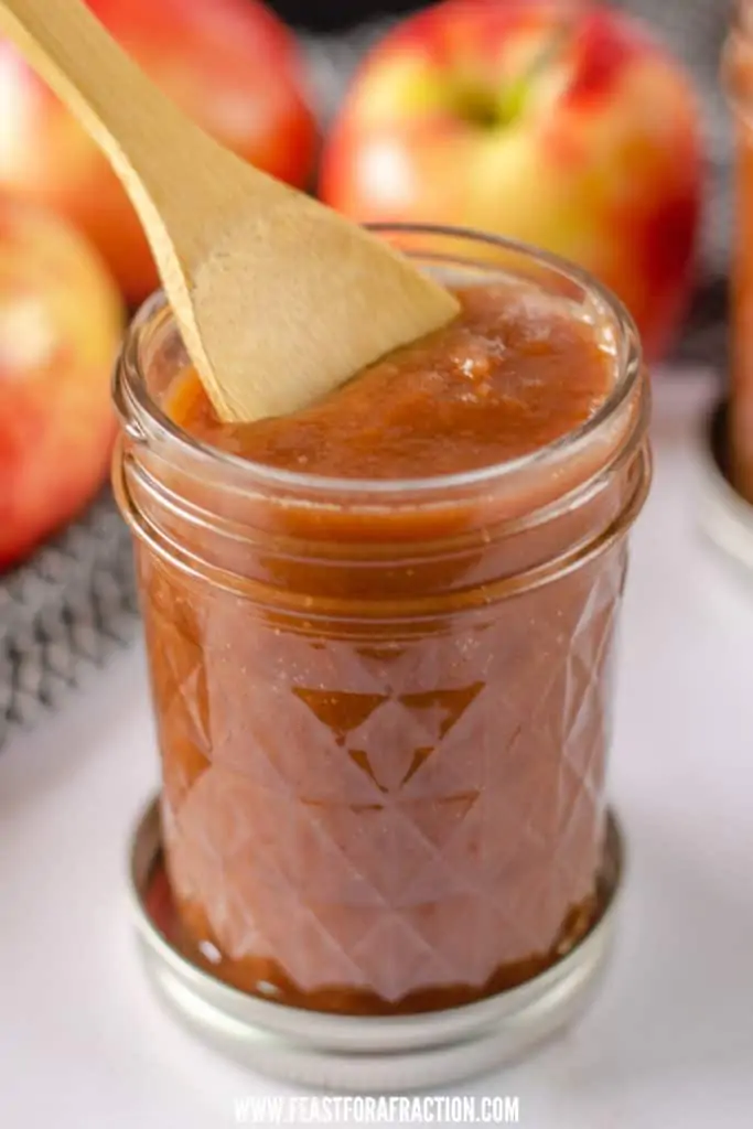 instant pot apple butter in glass jar with wooden spoon