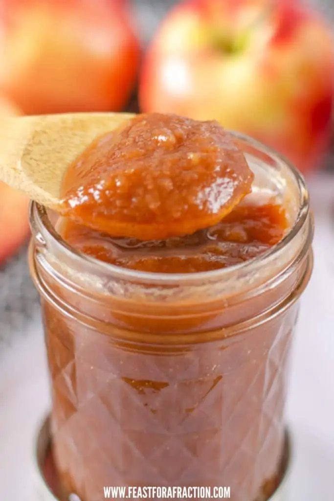 Instant pot apple butter in jar with wooden spoon scooping