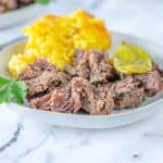 shredded mississippi pot roast on white plate with corn casserole