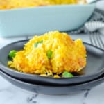 square image of corn casserole on black plate garnished with green onions