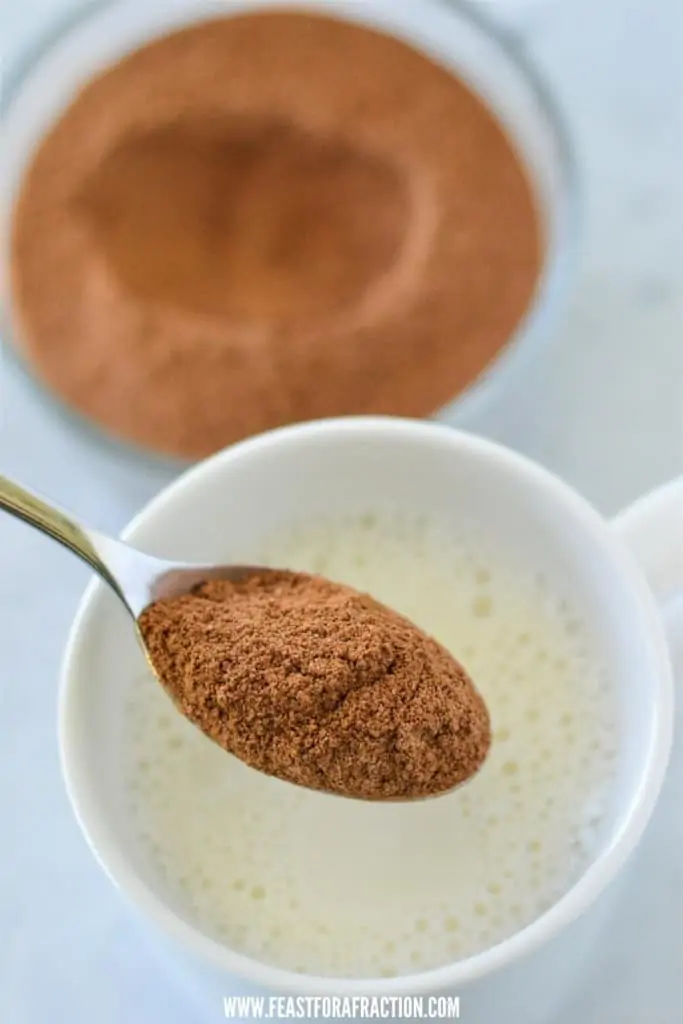 hot chocolate mix being mixed into a glass of milk