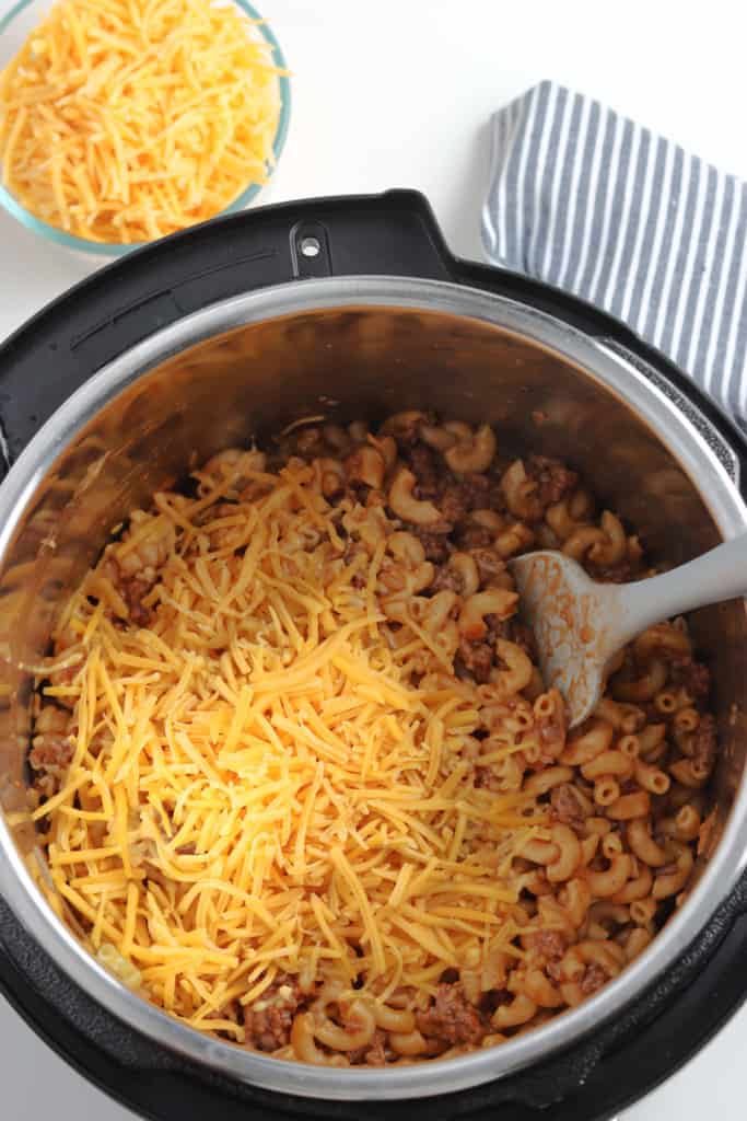 cooked beef and noodles in instant pot topped with shredded cheese