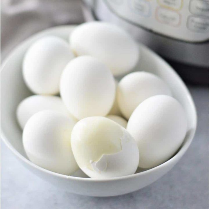 one peeled egg in a bowl with hard boiled eggs
