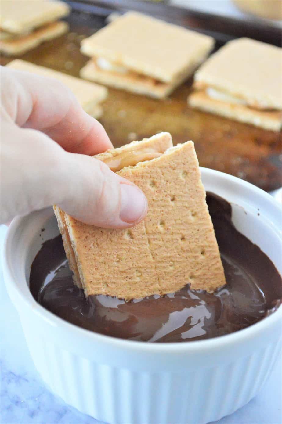 graham crackers with peanut butter and banana being dipped in melted chocolate