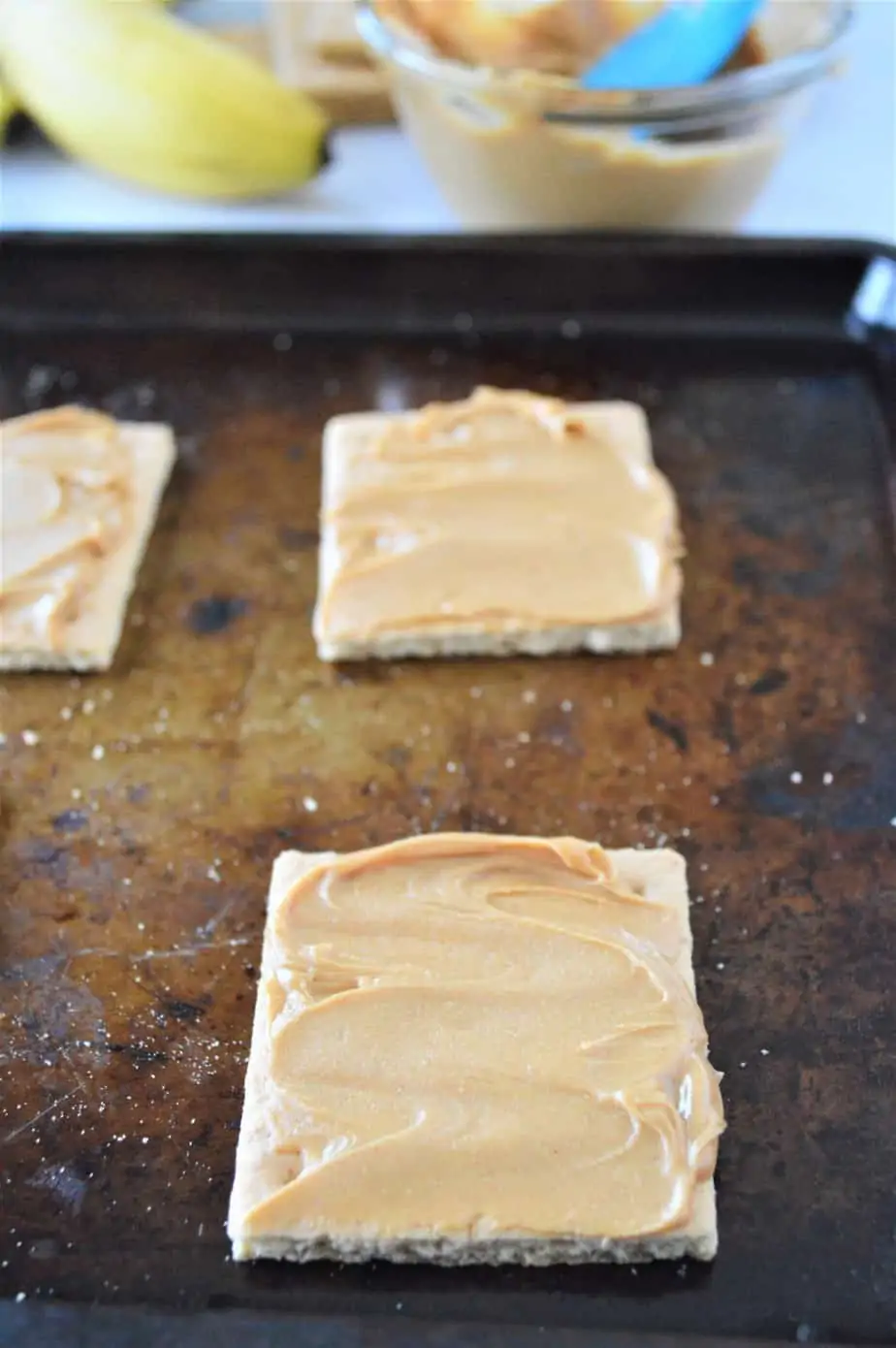 graham crackers on cookie sheet spread with peanut butter