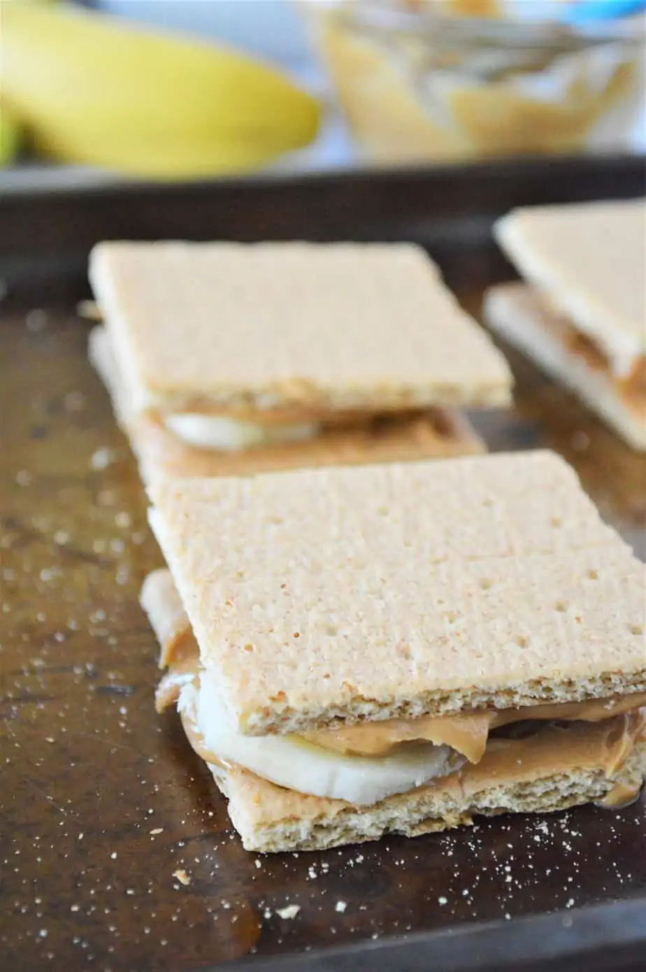 graham crackers with peanut butter and banana on cookie sheet