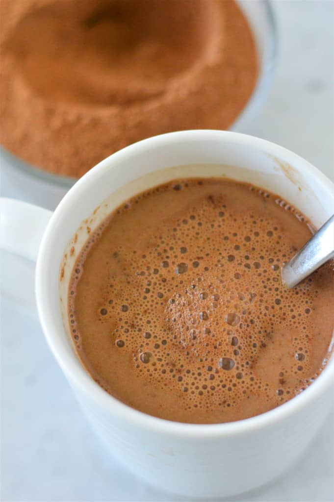 prepared hot chocolate recipe in white mug with mix in background