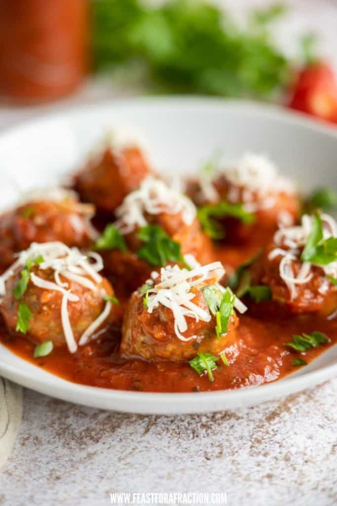 side view of baked meatballs in tomato sauce in white dish