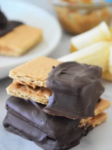 chocolate peanut butter banana crackers stacked on counter with peeled banana in background