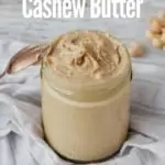 jar of homemade cashew butter on cloth napkin with spoon leaning against jar and title text