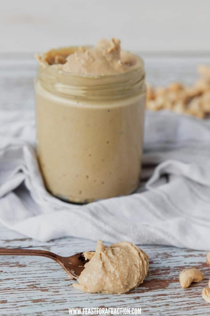 cashew butter in jar with spoon of nut butter on counter