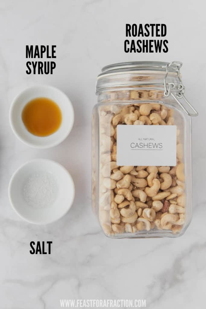 roasted cashews in glass jar with bowls of maple syrup and salt
