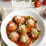 prepared baked meatballs in white bowl with tomato sauce parmesan cheese and chopped parsley with title text "Oven Baked Meatballs"